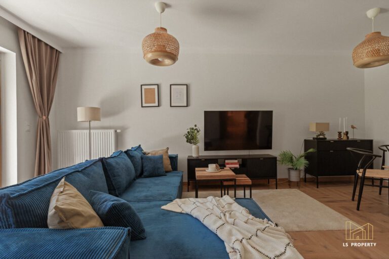 Pokój dzienny z dużą, granatową kanapą i telewizorem