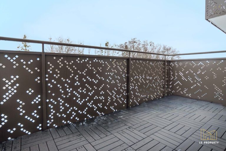 Balkon z nowoczesną balustradą wyłożony kafelkami imitującymi drewno.